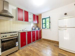 a kitchen with red cabinets and a white refrigerator at House with Two Bedrooms Dinko HH in Višnjica +7 photos