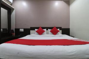 a bedroom with a large bed with red pillows at Hotel O Shri Sai Niwara Lodge in Dhule