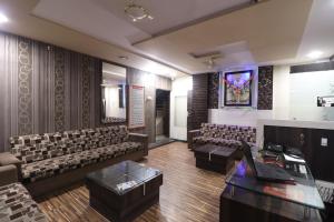 a waiting room with chairs and a table and a monitor at Hotel O Shri Sai Niwara Lodge in Dhule