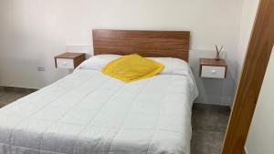 a white bed with a yellow pillow on it at Departamento Abril Sierras in Tandil +2 photos