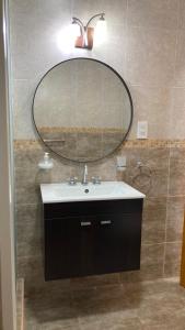 a bathroom with a sink and a large mirror at Departamento Abril Sierras in Tandil