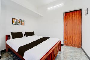 コインバトールにあるSuper Hotel O Neelambur Near PSG ITechのベッドルーム1室(ベッド1台付)、木製のドア