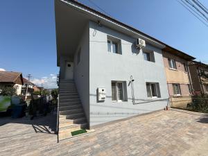 a white house with a staircase in front of it at Bee house 11 in Odorheiu Secuiesc