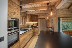 ムジェーヴにあるLuxury Megeve Chalet 4BR 10p Fireplace Mountain Views and Gardenの木製の壁と黒いカウンタートップが備わるキッチン