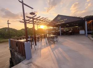 un patio con mesas y sillas y puesta de sol en Intimate Riverside Resort Vang Vieng, en Vang Vieng