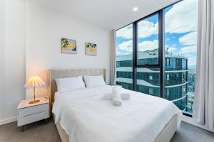 a bedroom with a white bed and a large window at Spacious 4BR penthouse in Box Hill Free Parking x 2 in Box Hill