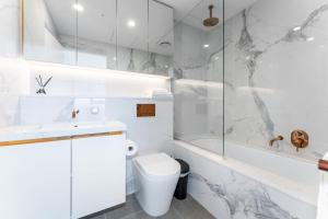 a white bathroom with a toilet and a shower at Spacious 4BR penthouse in Box Hill Free Parking x 2 in Box Hill