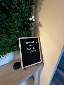 a sign sitting on a table next to a plant at Hidden Gem Hot tub pool table - EV charger Sleep number Bed in Perry Manor
