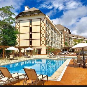 a hotel with a swimming pool in front of a building at Apartamento com varanda e vista da Pedra Azul in Domingos Martins