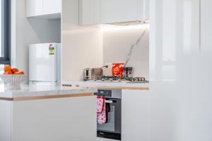 a kitchen with white cabinets and a stove top oven at Spacious 4BR penthouse in Box Hill Free Parking x 2 in Box Hill