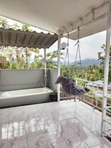 Ban Hin Hakบ้านสวนคึดฮอดโฮมสเตย์ ศรีสวัสดิ์ กาญจนบุรี的门廊配有秋千和浴缸