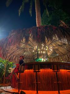 a man sitting in a chair in front of a straw hut at Minkanta Central Hostel in Minca