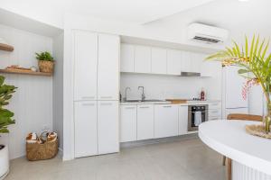 a white kitchen with white cabinets and a sink at Luxe at Oshen Yeppoon in Yeppoon