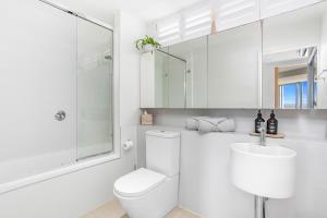 a white bathroom with a toilet and a sink at Luxe at Oshen Yeppoon in Yeppoon