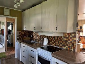 una cucina con mobili bianchi e un forno a piano cottura di 5 person holiday home in ADELSÖ ad Adelsö
