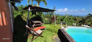 a backyard with a swimming pool and a chair and a house at Hélios Zion in Capesterre-Belle-Eau