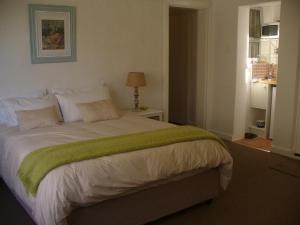 a bedroom with a bed with a green blanket on it at Royal at Sea in Muizenberg