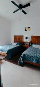 een slaapkamer met twee bedden en een plafondventilator bij El paraíso del descanso in El Jobo