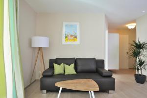 ein Wohnzimmer mit einem schwarzen Sofa und einem Tisch in der Unterkunft Linden Palais Heiligendamm Apartments in Heiligendamm