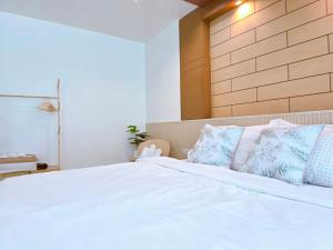 a bedroom with a white bed with blue pillows at The beach bangsaen condo daily room Poolside in Ban Bang Saen (1) +2 photos