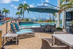 a pool with chairs and a table and an umbrella at Spacious Mantra Hotel Room in Urangan