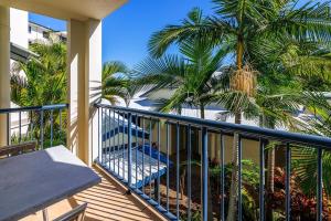 a balcony with palm trees and a bench on it at Spacious Mantra Hotel Room in Urangan