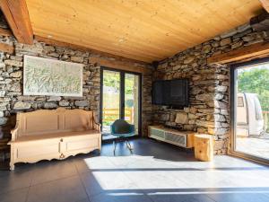 Cette chambre dispose d'un mur en pierre, d'une télévision et d'une chaise. dans l'établissement Chalet pyrénéen chalet à Soulan pour 12 pers., WiFi, proche ski - FR-1-296-528, à Soulan