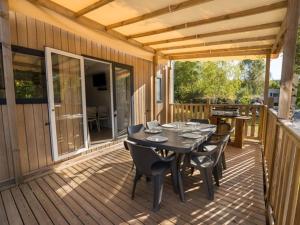 una terrazza in legno con tavolo e sedie. di Mobil home 36m² avec terrasse - 6 personnes, 3 chambres - API-1-52-530 a Barbey-Séroux