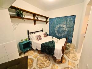 Un pequeño dormitorio con una cama y una mesa. en Villa Pachamama Hospedaria - Praia do Rosa, en Praia do Rosa