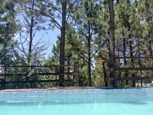 a swimming pool with a wooden fence and trees at Terrazas del Pinar, Loft en bosque serrano in Villa Ciudad de America
