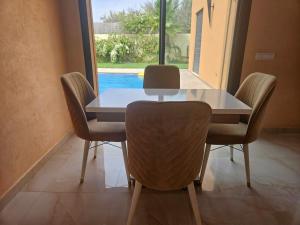 a dining room table and chairs with a view of a pool at Villa Familiale in Marrakech
