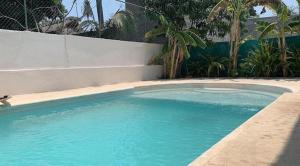 a large blue swimming pool next to a white wall at Casa del Alma in Puerto Escondido