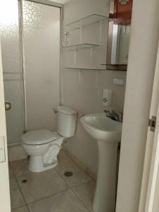 a white bathroom with a toilet and a sink at Casa en Lambayeque in Lambayeque