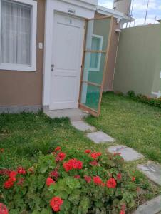 a door to a house with red flowers in the grass at Casa en Lambayeque in Lambayeque