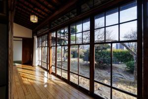 een lege kamer met grote ramen in een huis bij Guest House景 in Kumamoto
