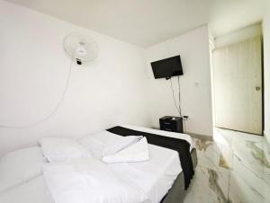 a white room with a bed and a tv at Casa Eclat in Medellín