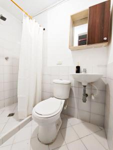 a white bathroom with a toilet and a sink at Casa Eclat in Medellín