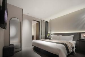 une chambre avec un grand lit blanc et une télévision dans l'établissement JN Hotel, Guanyinqiao Pedestrian Street, Chongqing, à Chongqing