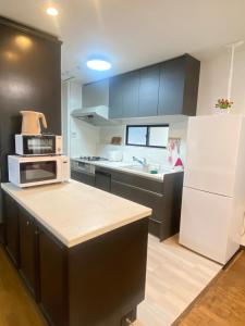 a kitchen with a white refrigerator and a microwave at raikoエレベーター付き大人数向け一棟貸切宿 in Nishi-biwajima