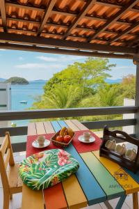 a table with a bowl of fruit and a view of the ocean at Anfitriões Angra- Flat com Vista Espetacular na Praia Grande in Angra dos Reis