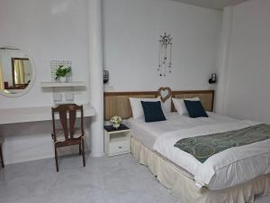 a bedroom with a bed and a table and a mirror at Suwita House in Nai Yang Beach