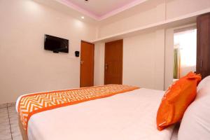a bedroom with a large white bed with an orange blanket at Premium Villas and Appartments thekady in Thekkady