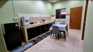 a small kitchen with a table and chairs in it at Homestay Kuala Berang Bonda Full Aircond Wifi & Netflix in Kuala Berang