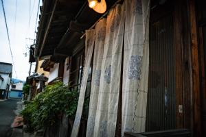 a curtain is on the side of a building at A 270-year-old soy sauce maker and a 100-year-old house collaborate to create Kamebishi-tei in Higashikagawa