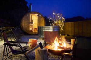 Una fogata en un patio con algunas sillas y barriles. en SHELTER君津 星が降りそそぐ千葉県Villa 最大8名 都心から70分 吹抜け貸切サウナ 雨でもBBQ 天体観測, en Kimitsu