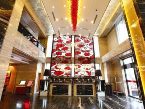 a lobby with a large wall with a chandelier at The Prosperous City Hotel Weifang in Weifang