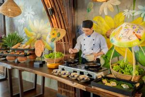 a chef preparing food on a stove in a restaurant at The Signature Hotel Nha Trang in Nha Trang