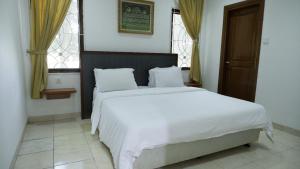 a bedroom with a large white bed and two windows at Villa Dalia Puncak Nc3-31 in Cikundul