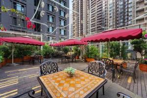 an outdoor patio with tables and chairs and red umbrellas at James Joyce Coffetel Chengdu Jianshe Road Dongjiao Jiyi Square in Chengdu