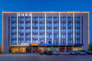 un grande edificio con auto parcheggiate in un parcheggio di 7Days Inn Tianjin Airport NO.1 Bridge Branch a Tianjin